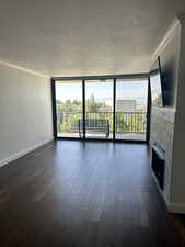 Unfurnished living room with expansive windows, plenty of natural light, a textured ceiling, dark wood finished floors, and a fireplace