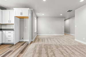 Kitchen with recessed lighting, white cabinets, dark countertops, and baseboards
