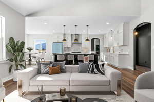 Living area featuring arched walkways, dark wood-style flooring, recessed lighting, baseboards, and lofted ceiling