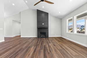 Unfurnished living room featuring vaulted ceiling, ceiling fan, recessed lighting, dark wood finished floors, and a fireplace
