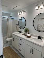 Full bathroom with double vanity, a textured ceiling, toilet, shower / tub combo with curtain, and marble finish flooring