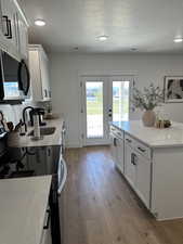 Kitchen with stainless steel microwave, a sink, a textured ceiling, wood-type flooring, and white cabinetry