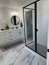 Bathroom featuring marble finish floors, vanity, a stall shower, and a textured ceiling