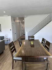 Dining space featuring stairs, light wood-style flooring, a textured ceiling, and recessed lighting
