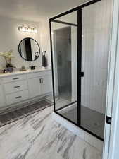Full bathroom with marble finish floors, vanity, and a stall shower