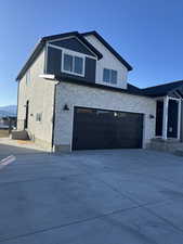 View of front of property featuring stone siding, board and batten siding, and concrete driveway