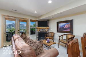 Living area with carpet, french doors, baseboards, a stone fireplace, and recessed lighting