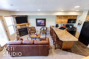 Kitchen with black appliances, a sink, a textured ceiling, open floor plan, and a fireplace