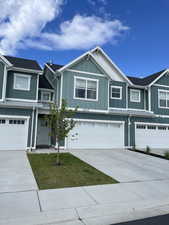 View of front of property with a garage, board and batten siding, driveway, and a front lawn