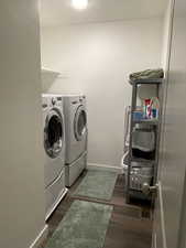 Laundry room featuring separate washer and dryer, baseboards, and dark wood finished floors
