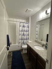 Full bath with vanity, toilet, shower / bathtub combination with curtain, and wood finished floors