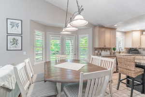 Informal dining area with lofted ceiling, recessed lighting, and light tile floors