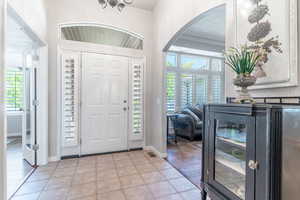 Foyer entrance featuring lots of natural light, crown molding, and vaulted ceiling