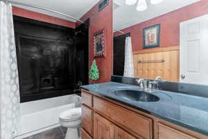 Bathroom featuring vanity, shower / bath combo and wainscoting