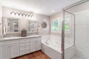 Recently remodeled Primary bath with a stall shower, a whirlpool tub, double vanity, and hardwood floors