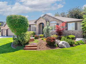 View of front facade with brick siding, concrete driveway, a front yard, and a garage