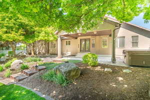Back of property featuring french doors, stucco siding, covered patio, and hot tub