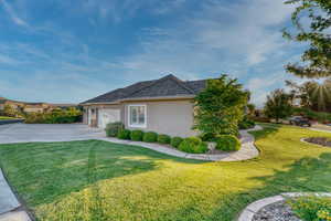 View of side of property with concrete driveway, an attached garage, stucco siding, and a lawn