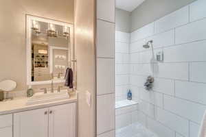Full bath featuring tiled shower, vanity, and a chandelier
