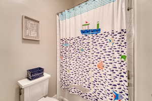 Full bathroom with toilet and a shower with shower curtain