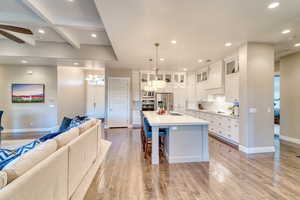 Kitchen featuring open floor plan, stainless steel appliances, custom exhaust hood, a sink, and recessed lighting