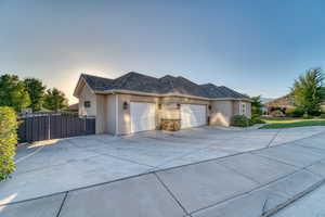 Property exterior at dusk with a garage, stucco siding, and concrete driveway