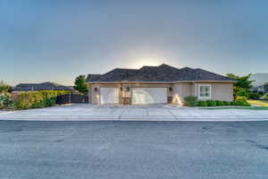Ranch-style house featuring an attached garage, stucco siding, and driveway