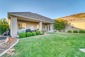Rear view of property featuring french doors, stucco siding, and a yard