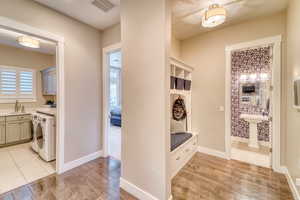 Mudroom featuring a sink, light wood-style floors, washing machine and clothes dryer, and baseboards