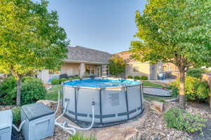 Back of property featuring an outdoor pool, stucco siding, and a shingled roof