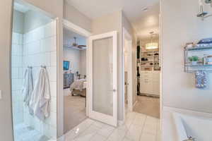 Bathroom featuring connected bathroom, ceiling fan, a bathtub, a walk in closet, and a tile shower