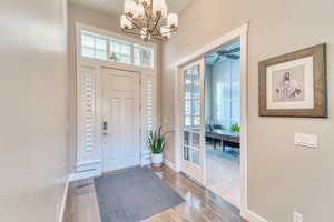 Entryway with a chandelier, healthy amount of natural light, baseboards, and wood finished floors