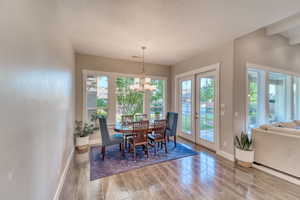 Dining space with wood finished floors, baseboards, a chandelier, and a textured ceiling