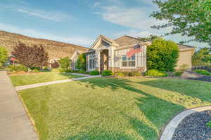 View of front facade with a front yard and stone siding