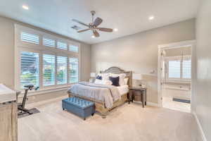 Carpeted bedroom featuring multiple windows, baseboards, recessed lighting, and ensuite bath