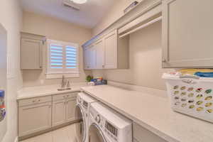 Washroom featuring washing machine and dryer, cabinet space, a textured ceiling, and light tile patterned floors