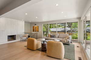 Living room featuring wood finished floors, recessed lighting, and a glass covered fireplace