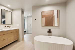 Bathroom featuring recessed lighting, vanity, a freestanding bath, and baseboards