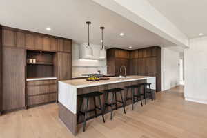 Kitchen featuring modern cabinets, light countertops, open shelves, light wood-style floors, and recessed lighting