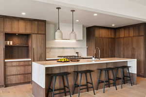 Kitchen featuring modern cabinets, a sink, light countertops, a breakfast bar, and recessed lighting