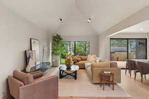 Living area featuring light wood-style flooring, high vaulted ceiling, and recessed lighting
