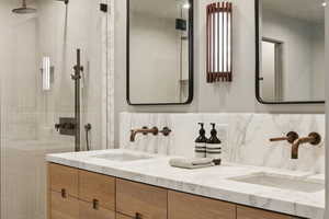 Bathroom featuring double vanity, a tile shower, and tasteful backsplash