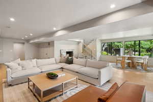 Living area with light wood-style flooring, recessed lighting, stairway, and a fireplace