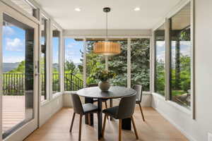 Sunroom / solarium with healthy amount of natural light, wood finished floors, baseboards, a mountain view, and recessed lighting