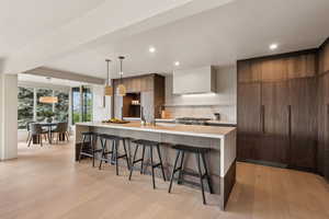 Kitchen with modern cabinets, a kitchen breakfast bar, decorative backsplash, light countertops, and light wood-style flooring