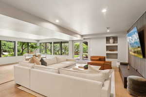 Living area with plenty of natural light, recessed lighting, light wood-type flooring, and built in features