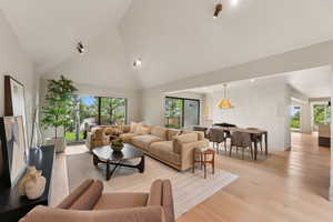 Living area with high vaulted ceiling, light wood finished floors, and recessed lighting
