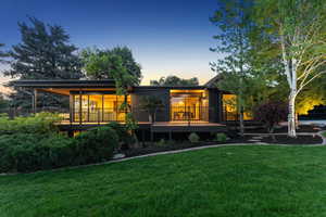 Back of property at dusk featuring a lawn and a wooden deck