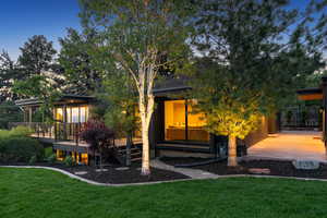 Rear view of house featuring a wooden deck, a yard, and driveway