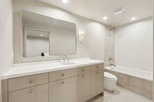Full bath featuring toilet, tiled shower / bath combo, vanity, recessed lighting, and tile patterned floors
